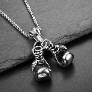 Silver boxing glove pendant necklace in stainless steel displayed on a black stone base