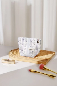 Detail of floral makeup bag with golden flower zipper and elegant brand label