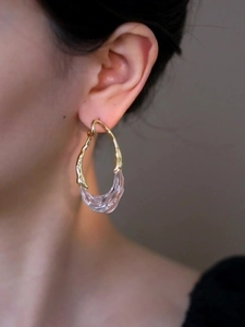 Détail des boucles d'oreilles en résine plaquée or 18 carats portées par un mannequin