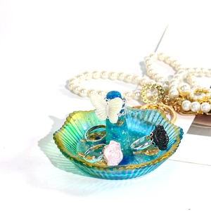 Detalle de bandeja de resina para anillos en forma de flor con borde de pan de oro