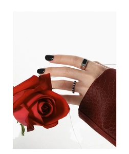 Detail of silver S925 rings with black epoxy inlay worn by model holding red roses