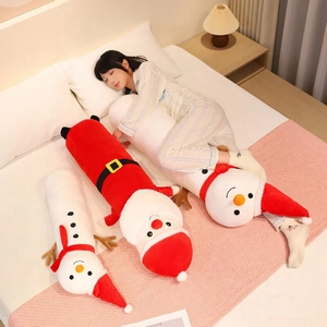 Detail of soft plush Christmas Santa and snowman body pillows on a cozy bedroom bed