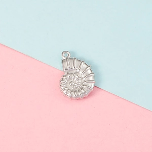 Detailed close-up of a silver nautilus shell pendant over a blue and pink background