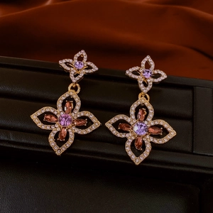 Exquisite gold clover earrings with purple and brown gemstones on black stand