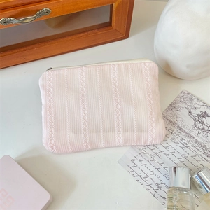 Detailed close-up of pink quilted cosmetic bag with delicate lace trim and zipper closure