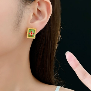 Close-up of vintage style green enamel rectangular earrings with red gem cross detail