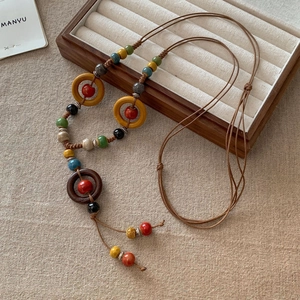 Dettaglio di collana boho con perline di legno e ciondoli in ceramica su lino