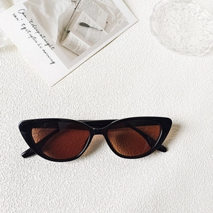 Detail of vintage cat-eye sunglasses with black frame and amber lenses on textured white background
