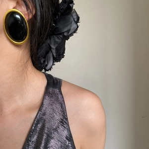 Close-up of vintage oval earring in gold and black resin worn by a fashion model
