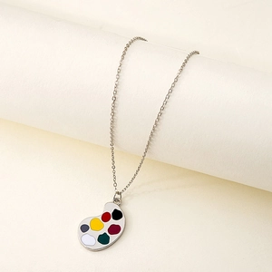 Detailed view of silver artist palette necklace with colorful enamel paint drops