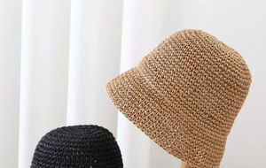 Detail shot of khaki and black woven straw bucket hats showing fine texture and weave