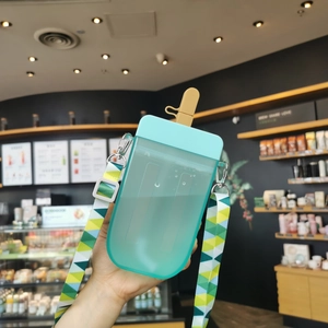 Creative cyan popsicle shaped water bottle with colorful shoulder strap held in a cafe