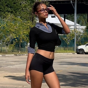 Détails du col et des poignets à carreaux bleu et blanc sur le crop top noir à manches