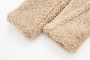 Close-up of the thick beige faux shearling texture and soft fleece fabric of the coat