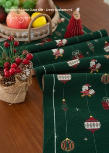Detail of green Christmas table runner with jacquard Santa and gift patterns on wood