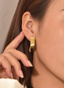 Close-up of gold-plated geometric wavy earring with pavé white zircon on model