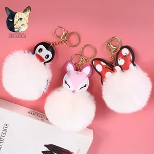 Detailed view of fluffy penguin and fox plush ball keychains with golden metal rings
