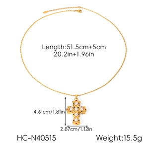 Detailed view of a gold cross pendant with pearls and gemstones on a stainless steel chain