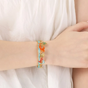 Detailed close-up of golden ocean-themed enamel bracelet with palm tree and seahorse motifs