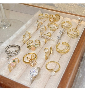 Detailed view of luxury gold ring set with heart, pearl, and zircon designs in a velvet box