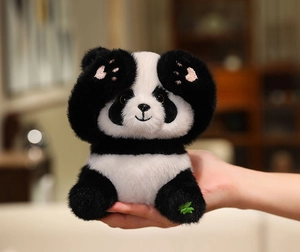 Close-up of plush panda toy with pink paw embroidery and a green four-leaf clover on foot
