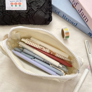 Macro view of cream-colored pencil case with chunky zipper and stationery inside