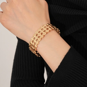 Close-up of golden hollow triple-layer oval cuff bracelet worn on a female wrist