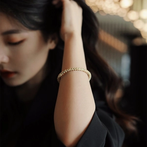 Detail shot of a minimalist gold beaded cuff bracelet on wrist with elegant bokeh lighting
