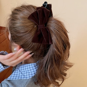 Close-up of deep brown velvet bow hair claw clip worn on a model hairstyle