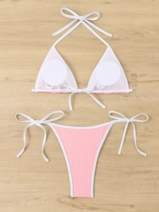 Detail of white triangle bikini top and pink ribbed texture bottoms on wood background
