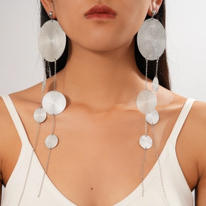 Dramatic silver long tassel earrings with metallic circular textures worn by a model