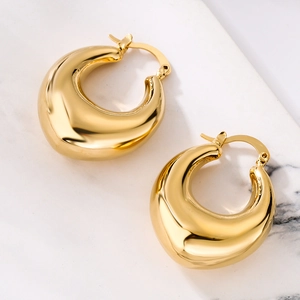 Macro detail of polished 18K gold plated thick teardrop earrings on marble background