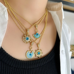 Three gold-plated necklaces with blue evil eye pendants worn by a female model