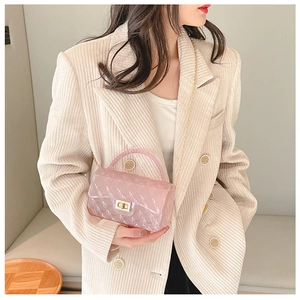 Detail view of pink quilted jelly bag with gold chain strap held by a model
