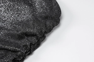 Détail du tissu en maille pailletée noire avec fronces et fils métalliques brillants