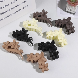 Flat lay of flower hair claws in matte earth tones including black, beige and tan