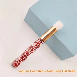 Detail view of red glitter eyelash cleaning brush with gold ferrule and white flat bristles