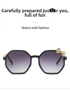 Close-up of kids octagonal sunglasses with gradient lenses and a gold metal bow detail