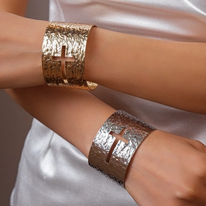 Detail of gold and silver hammered metal wide open bangles with cross cutout on models arm
