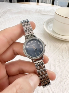 Close-up of silver metal ladies watch featuring a dark blue dial with rhinestone bezel