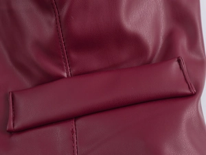 Detailaufnahme aus weinrotem PU-Leder mit feinen Nähten und hochwertiger Textur