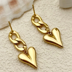 Minimalist gold heart chain stud earrings on white textured background with sea shell decor