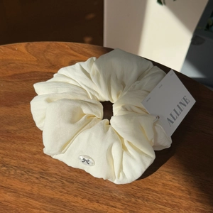 Close-up of cream-colored puff scrunchie with bow detail on a rustic wood surface