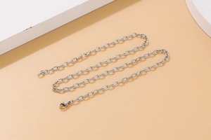 Close-up of interlocking silver chain necklace with hammered texture details on beige base