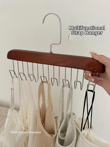 Detail of wooden multi-hook hanger organizing multiple white camisoles against a white wall