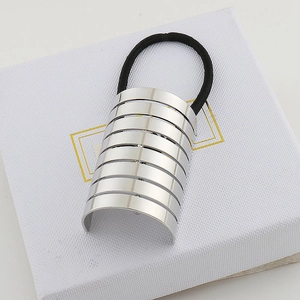 Detail of silver metallic striped ponytail cuff hair tie on white texture box