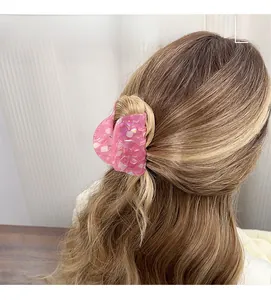 Macro detail of large pink marble acetate hair claw clip showing glossy pearlescent finish