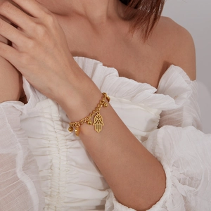 Gold stainless steel Hamsa Hand bracelet with heart charms worn by female model