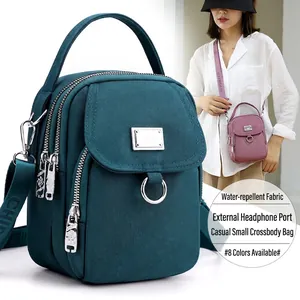 Waterproof nylon crossbody bag in teal blue with earphone hole and adjustable strap