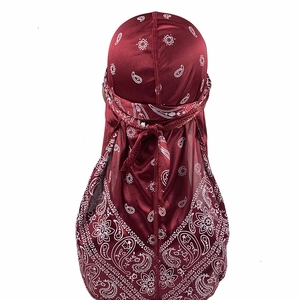 Detail of burgundy paisley silk durag with long tail straps on a white background